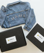 Denim jacket with 'MAMA' embroidery on a white surface with black boxes.