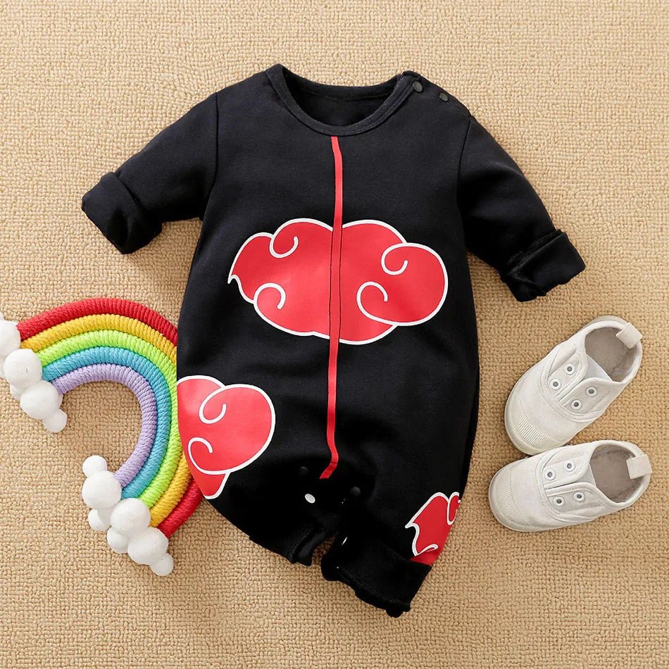 Black baby romper with red cloud design, rainbow toy, and white shoes on a beige surface