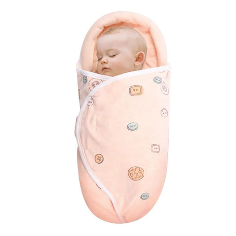 Newborn baby wrapped in a pink swaddle with cartoon designs.