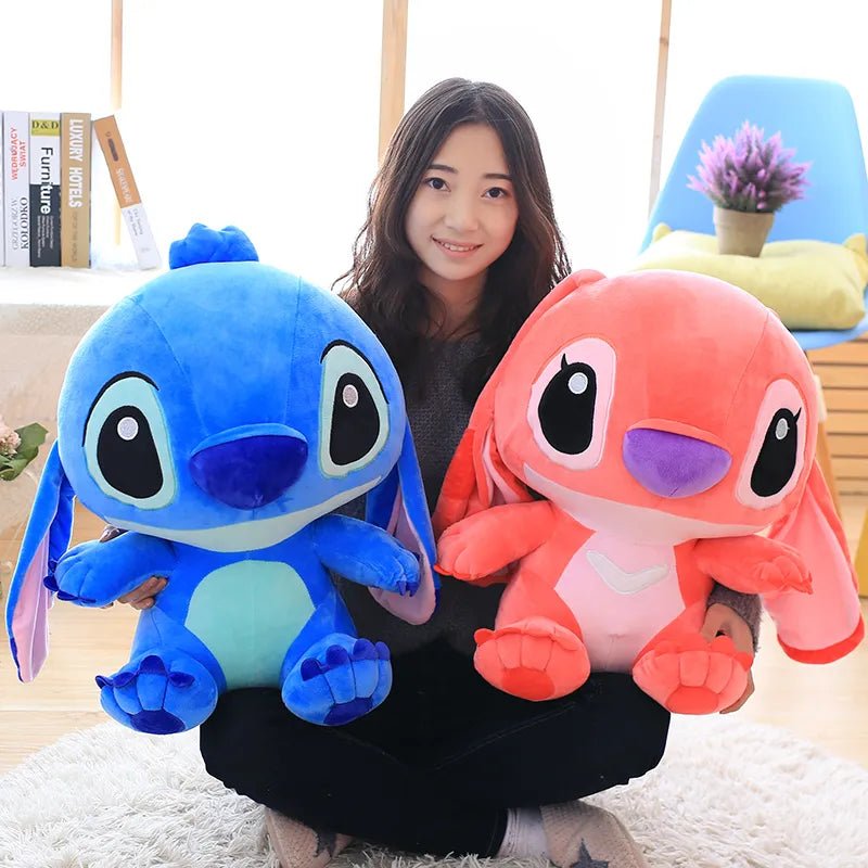 Person holding two plush toys, one blue and one pink, in a room setting.