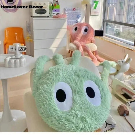 Green plush toy with googly eyes on a table in a room with decor elements.