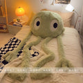 Large green plush toy resembling a cartoon character on a bed in a bedroom setting.