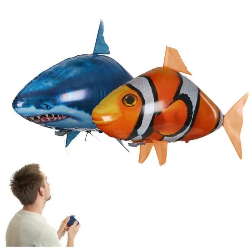 A man controlling a shark and a clownfish-shaped balloon toy.