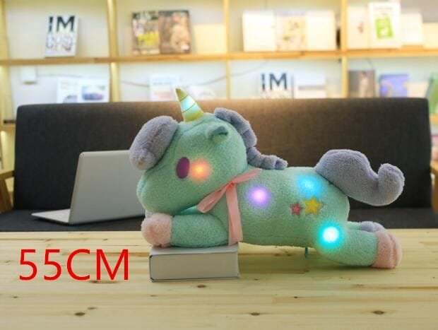 Light-up plush unicorn toy on a wooden surface.