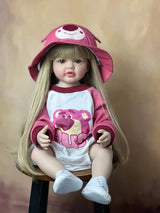 A doll wearing a pink cap and shirt with a bear design