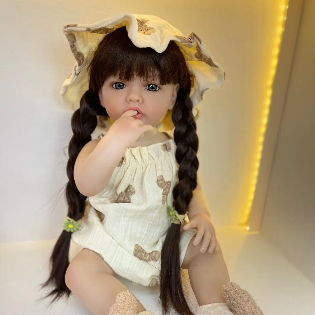 Doll with long braided hair wearing a white outfit with butterfly patterns on a light background.