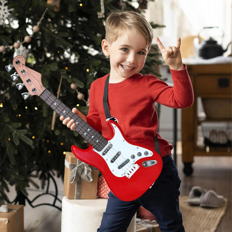 Child holding a red electric guitar in a festive indoor setting with Christmas decorations.