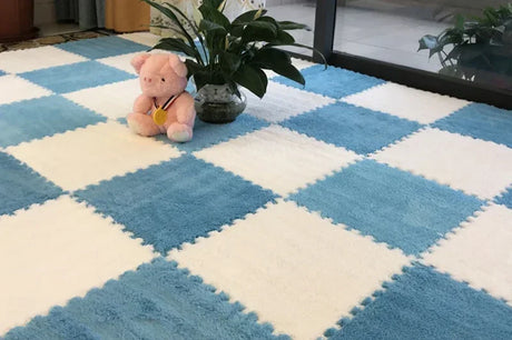 Blue and white checkered foam mat with a pink toy and plant on a checkered floor.
