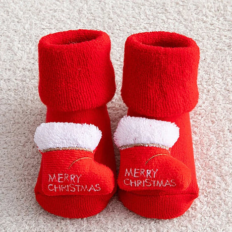 Red baby booties with white fur trim and 'Merry Christmas' text on a light background