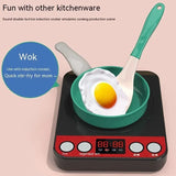 Induction cooker with a green wok and fried egg, featuring a toy spatula.