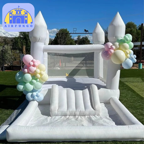 Inflatable castle with pastel balloon decorations on a grassy field.
