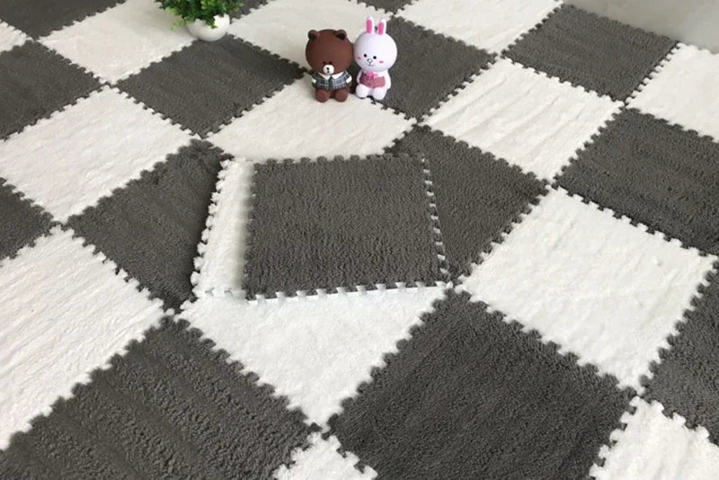 Checkered pattern of gray and white interlocking foam mats with small toys on top.