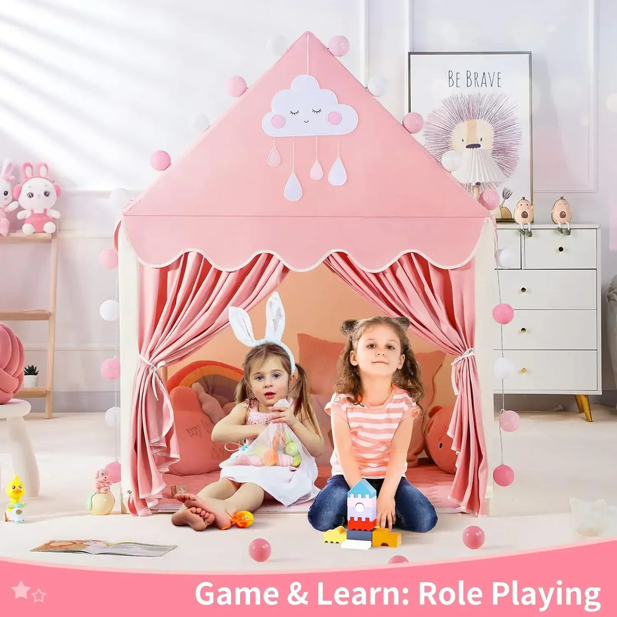 Two children playing inside a pink play tent in a room with toys and decor.