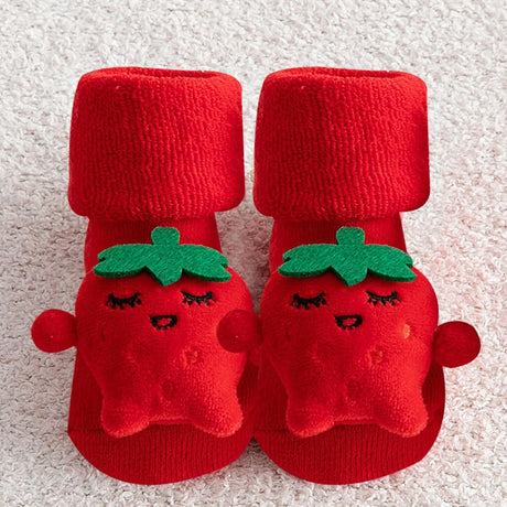 Red baby booties with tomato design on a textured surface