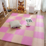 Pink and beige checkered foam mat on a wooden floor with a pillow and cup.