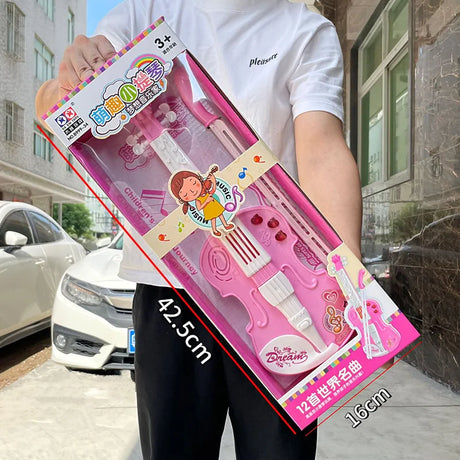 Person holding a pink toy violin set in packaging with measurements displayed.