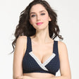 Woman wearing a navy blue bra with white polka dots and lace trim on a white background
