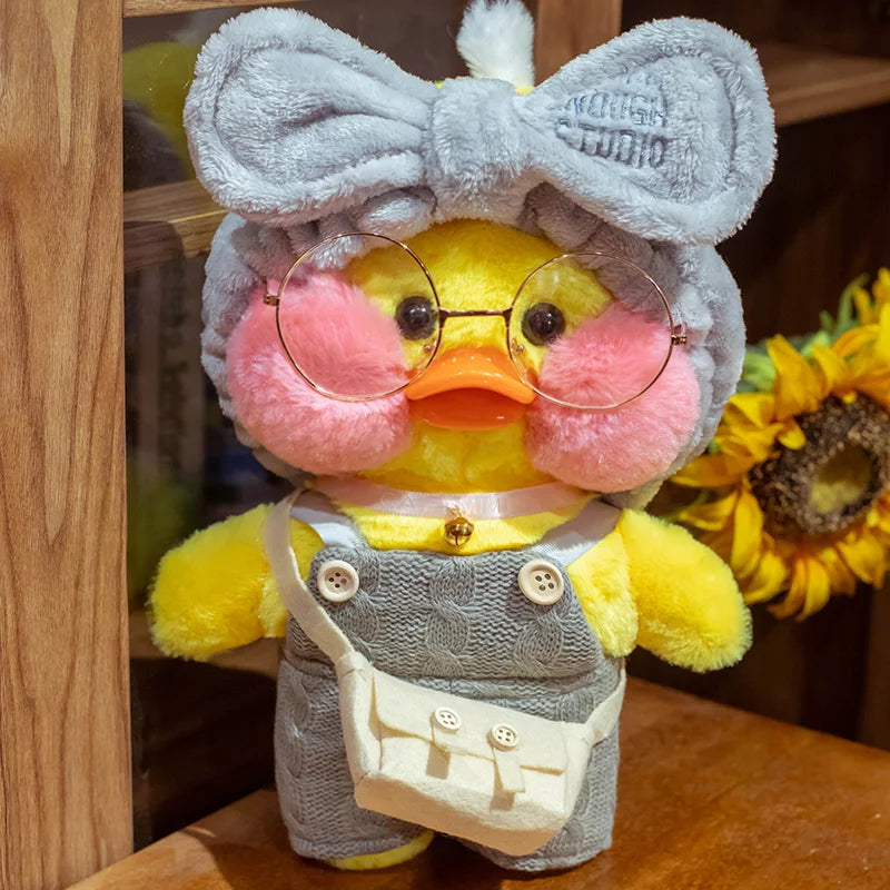 Plush toy duck with glasses and a bow tie on a wooden surface