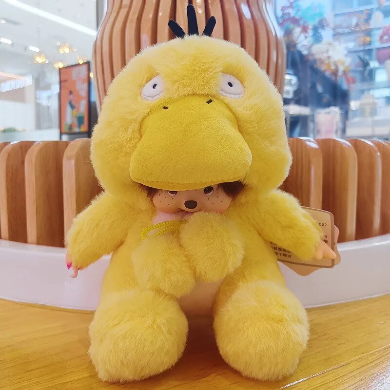 Yellow plush toy with a small person inside, held by a hand in an indoor setting.
