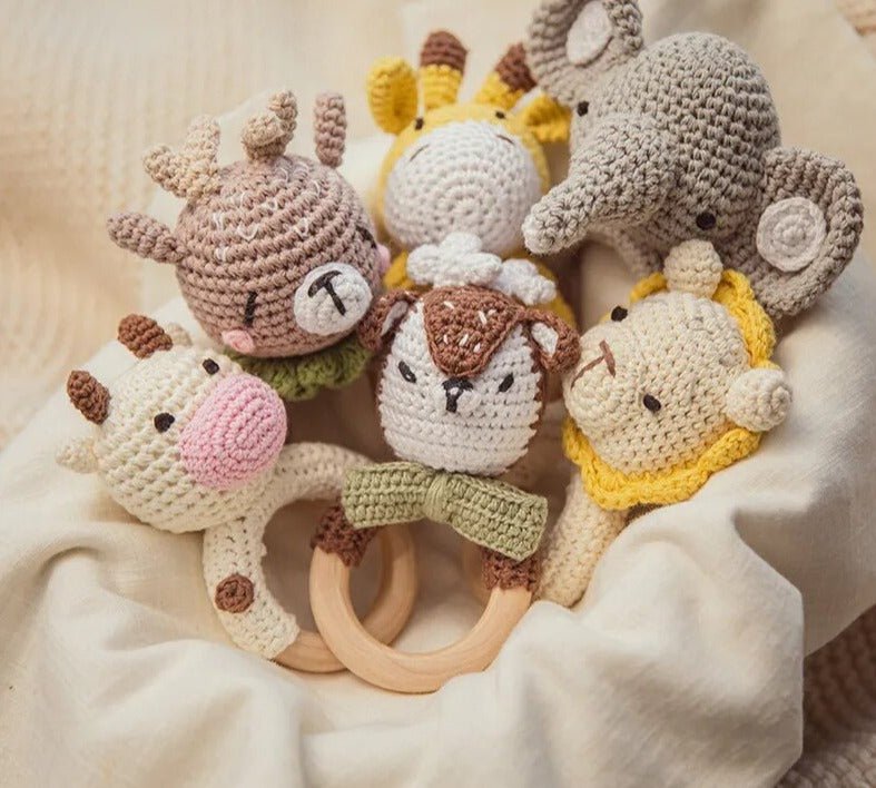 Set of crocheted animal toys with wooden rings on a soft beige background