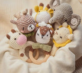 Set of crocheted animal toys with wooden rings on a soft beige background