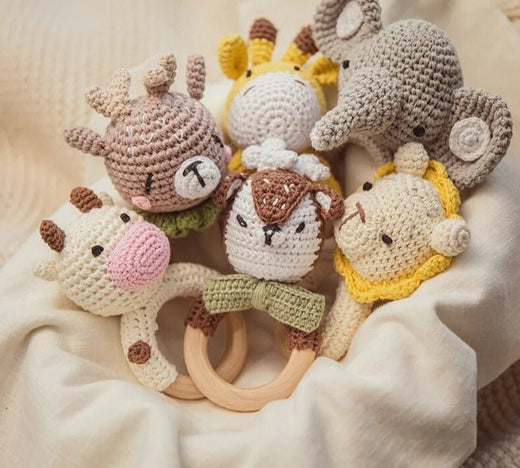 Set of crocheted animal toys with wooden rings on a soft beige background