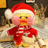 Stuffed toy duck wearing a red sweater, white scarf, and Santa hat on a decorative surface.