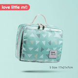 Small green bag with triangle pattern on a light blue background, featuring 'love little me' branding.
