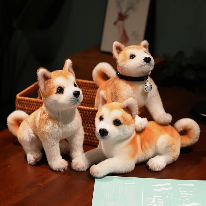 Three plush Shiba Inu dogs on a wooden surface.