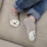 Gray socks with bear faces worn by a person on a beige couch.