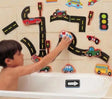 Child playing with bath toy set featuring roads, cars, and traffic lights in a bathtub.
