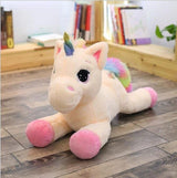 Plush unicorn toy with a rainbow mane on a wooden floor