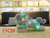 Light-up plush unicorn toy on a wooden surface with a blurred indoor background