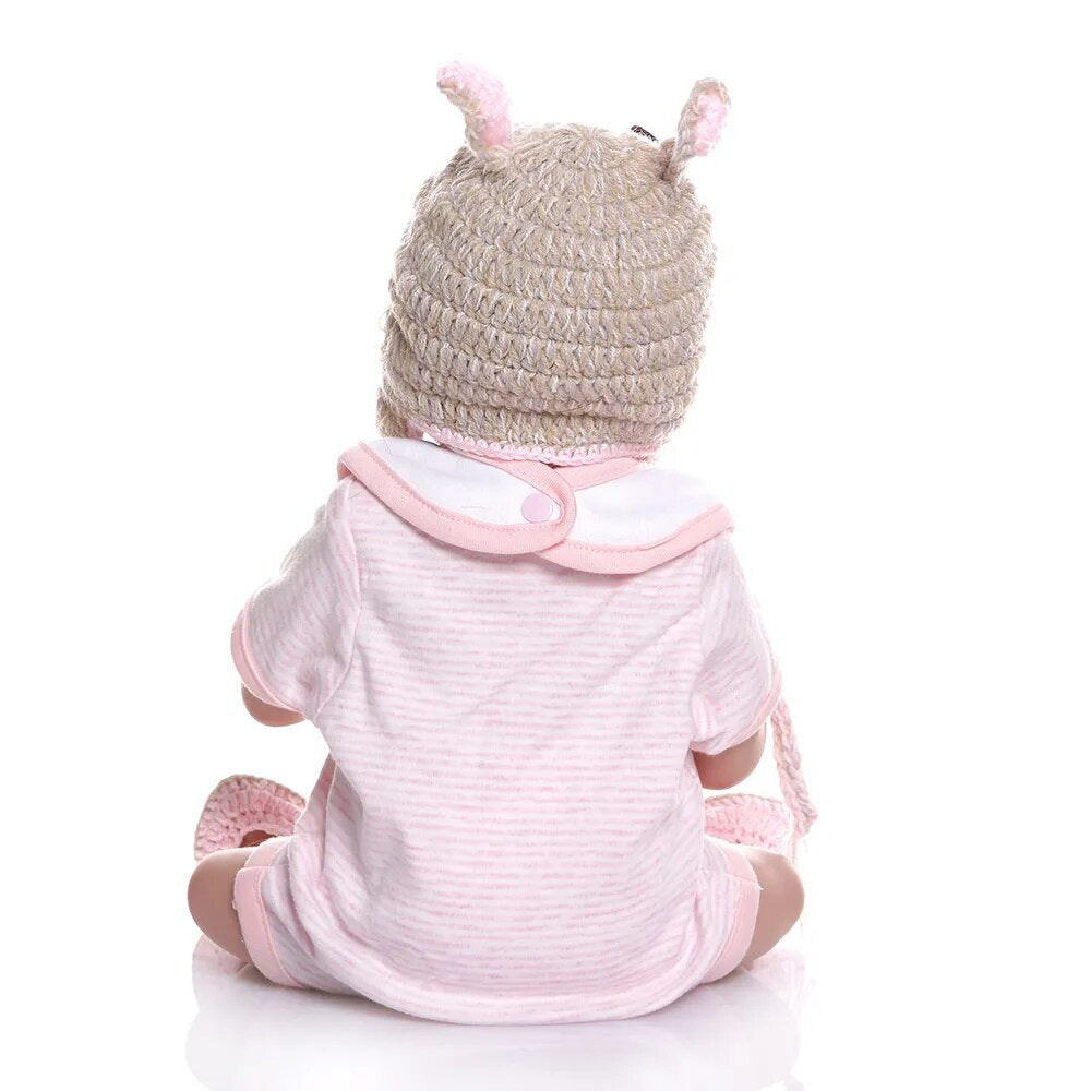Baby in a pink outfit with a striped pattern and a matching hat.
