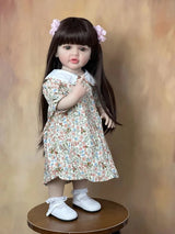 Doll wearing a floral dress and white shoes on a wooden surface