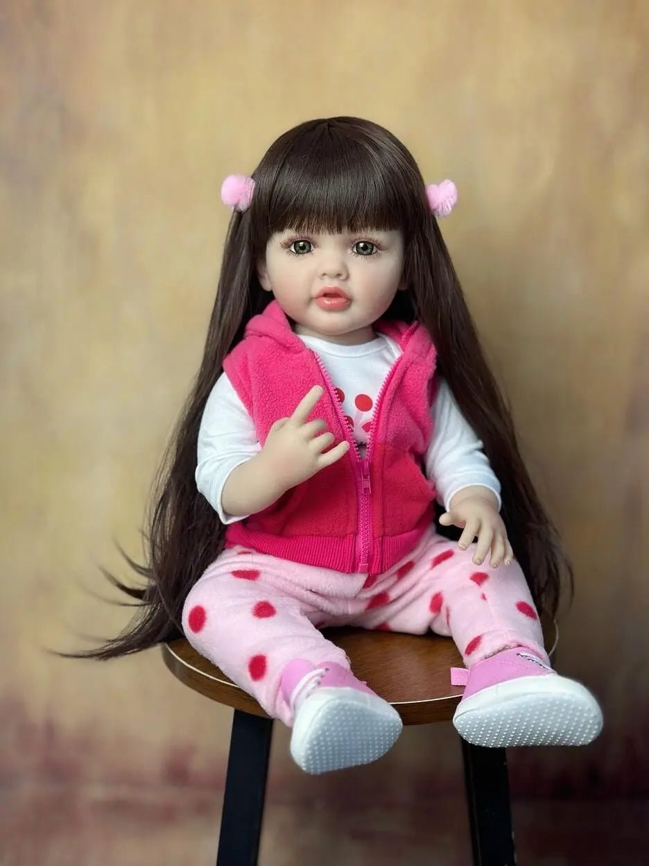  A doll with long brown hair wearing a pink outfit sitting on a chair.