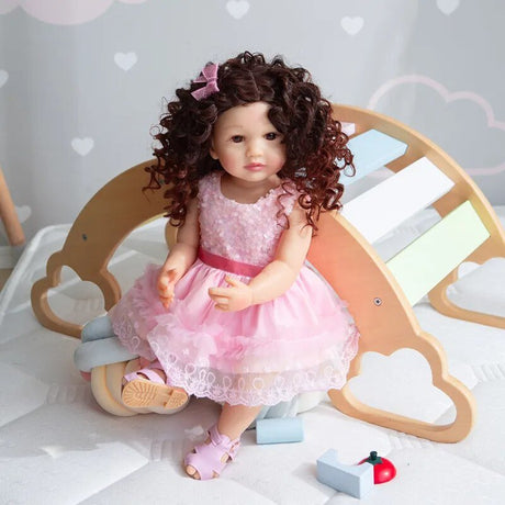 A doll in a pink dress sitting on a wooden place.