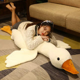 Person lying on a large plush swan toy on a checkered floor.
