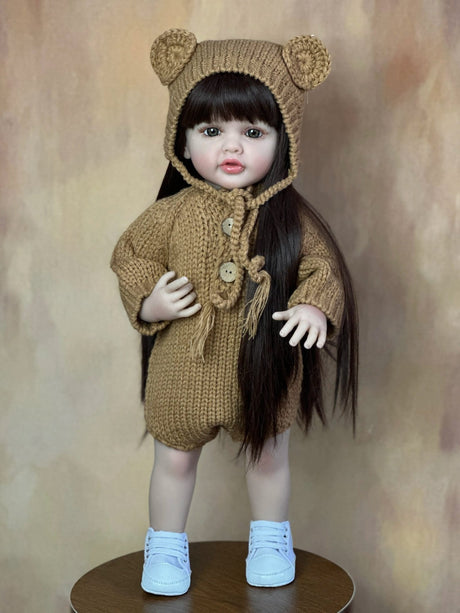  doll wearing a brown knitted outfit with bear ears on a brown background