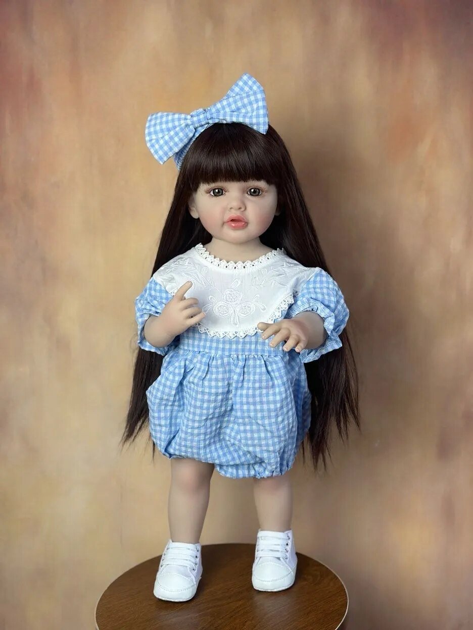 Doll with long dark hair wearing a blue checkered outfit and white shoes