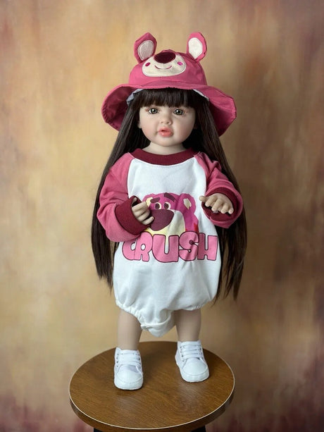 Child's doll wearing a pink and white outfit with a hat on a wooden stool 