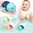 Baby playing with colorful turtle-shaped bath toys in water.