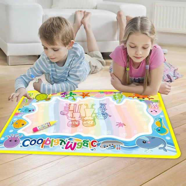 Two children playing with a colorful drawing mat on a wooden floor.