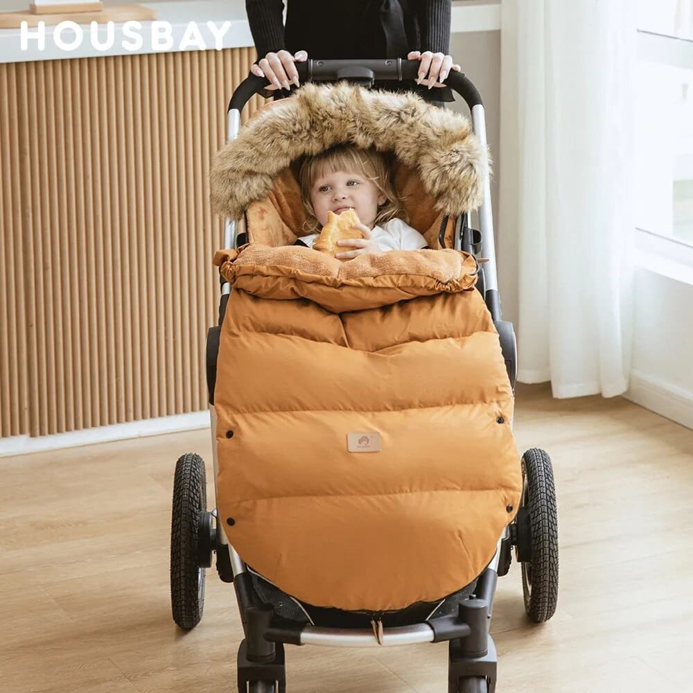 Child in a stroller with a mustard yellow footmuff, indoors.