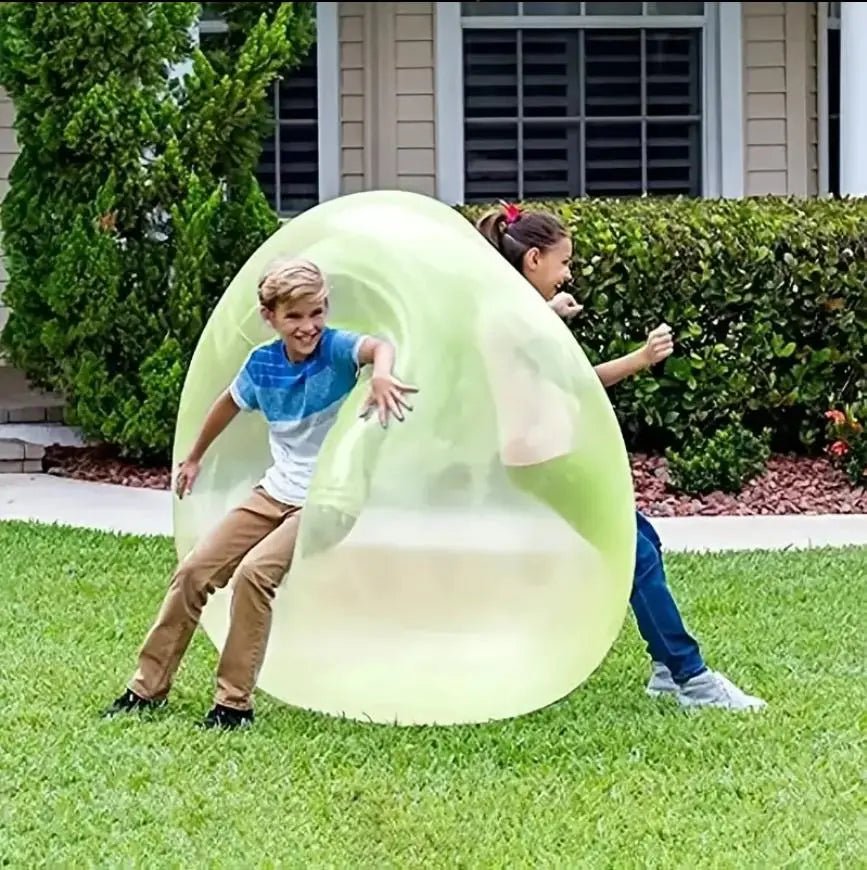 Two children playing with a large inflatable bubble in a backyard.