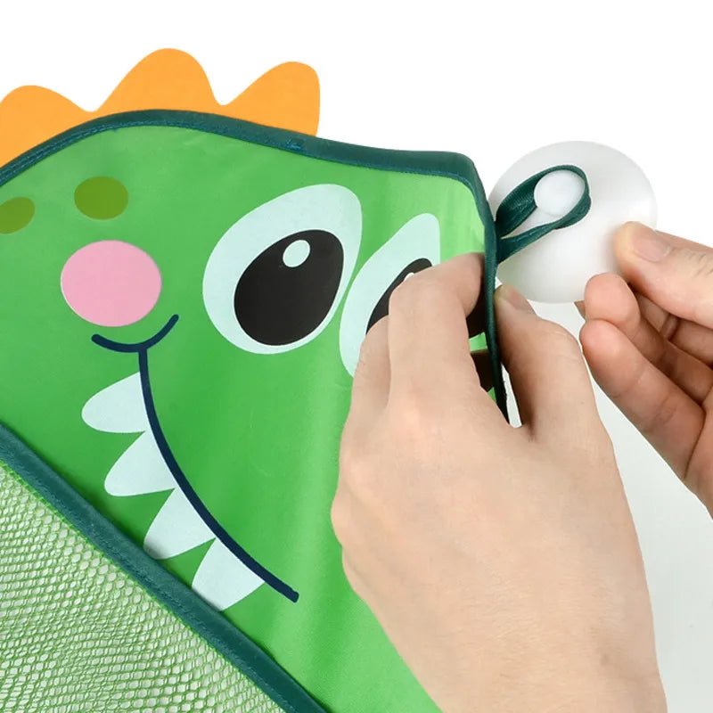 Person attaching a white ball to a green dinosaur-shaped bag.