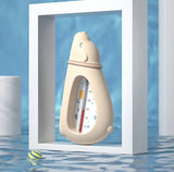 Bottle-shaped thermometer in a white frame with water and pool tiles in the background