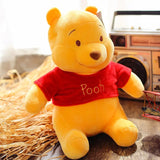 Plush toy bear wearing a red shirt with 'Pooh' on it, sitting next to a vintage boombox.
