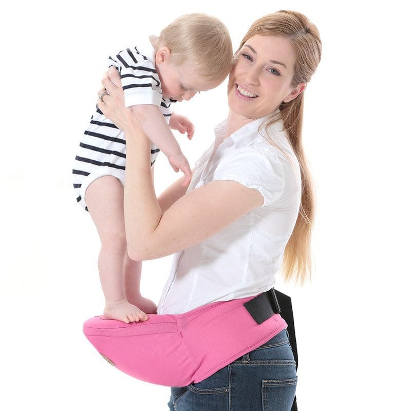 Woman holding a baby in a pink baby carrier against a white background