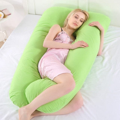 Woman lying on a green U-shaped pillow on a bed